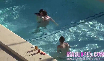 Beautiful dark-haired teen sucks two hard cocks and gets spitroasted in a pool