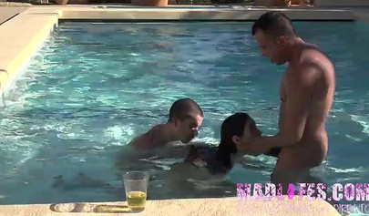 Beautiful dark-haired teen sucks two hard cocks and gets spitroasted in a pool