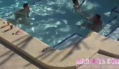 Beautiful dark-haired teen sucks two hard cocks and gets spitroasted in a pool