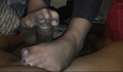 Nubile with sexy feet in nylons gives a footjob to a black cock until he cums