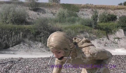 Ball-gagged blonde covered in mud posing outdoors