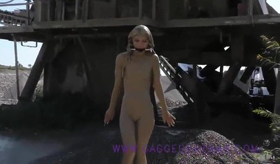 Ball-gagged blonde covered in mud posing outdoors