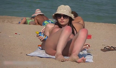 Beach spy catches a young brunette sunbathing fully naked
