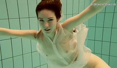 Beautiful teen swimming in the pool in her white sheer dress