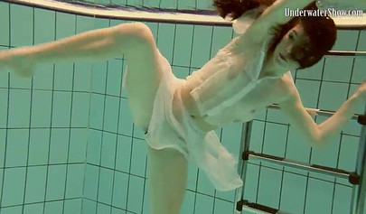 Beautiful teen swimming in the pool in her white sheer dress