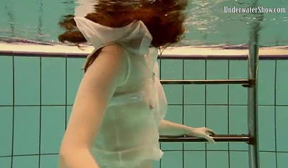 Beautiful teen swimming in the pool in her white sheer dress