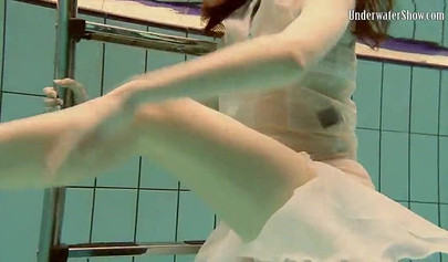 Beautiful teen swimming in the pool in her white sheer dress