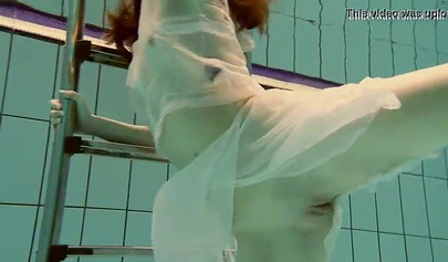 Beautiful teen swimming in the pool in her white sheer dress