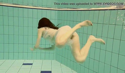 Beautiful teen swimming in the pool in her white sheer dress