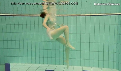 Beautiful teen swimming in the pool in her white sheer dress