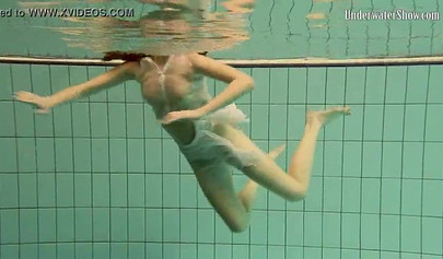 Beautiful teen swimming in the pool in her white sheer dress