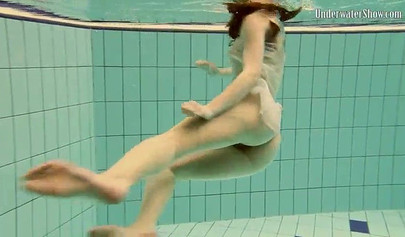 Beautiful teen swimming in the pool in her white sheer dress