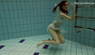 Beautiful teen swimming in the pool in her white sheer dress