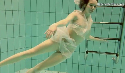 Beautiful teen swimming in the pool in her white sheer dress