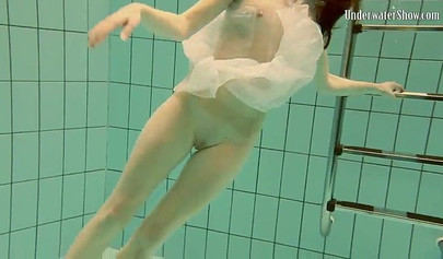 Beautiful teen swimming in the pool in her white sheer dress