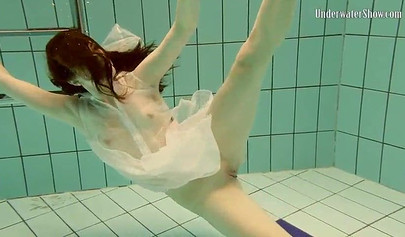 Beautiful teen swimming in the pool in her white sheer dress