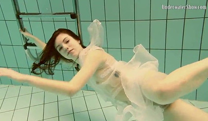 Beautiful teen swimming in the pool in her white sheer dress