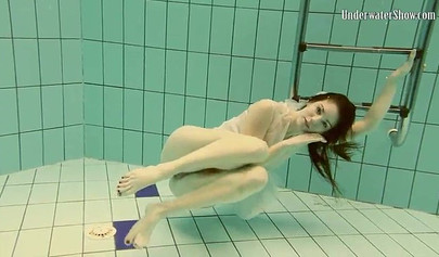 Beautiful teen swimming in the pool in her white sheer dress