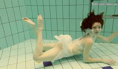 Beautiful teen swimming in the pool in her white sheer dress
