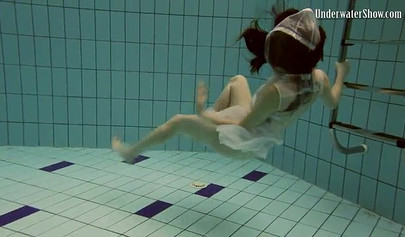 Beautiful teen swimming in the pool in her white sheer dress