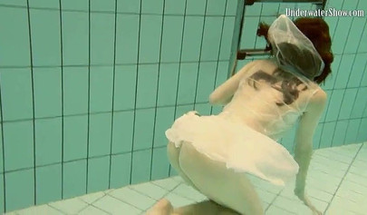 Beautiful teen swimming in the pool in her white sheer dress