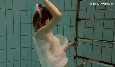 Beautiful teen swimming in the pool in her white sheer dress