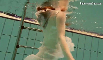 Beautiful teen swimming in the pool in her white sheer dress