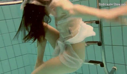 Beautiful teen swimming in the pool in her white sheer dress